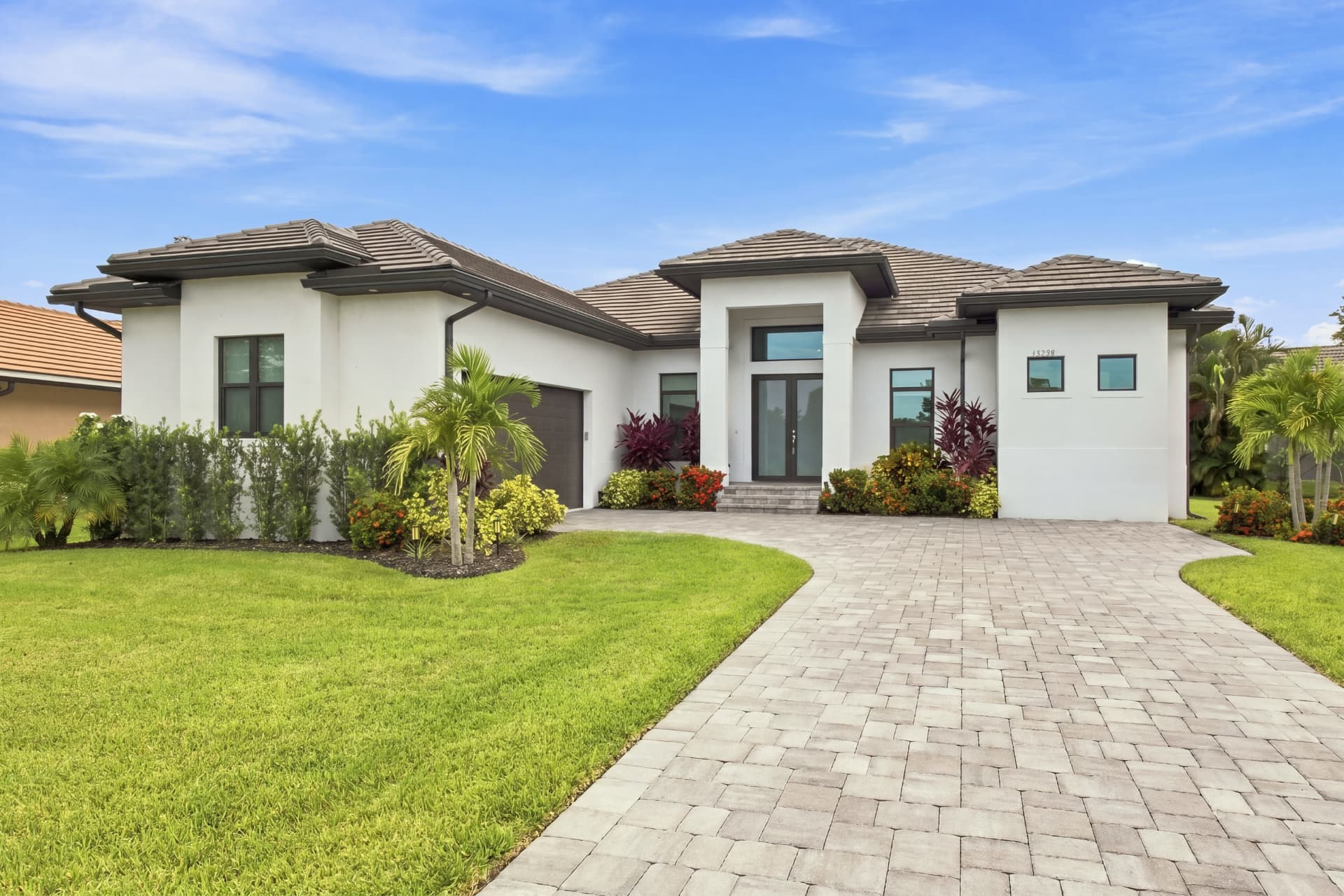 Front exterior of a Southwest Florida home with paver driveway and palm landscaping