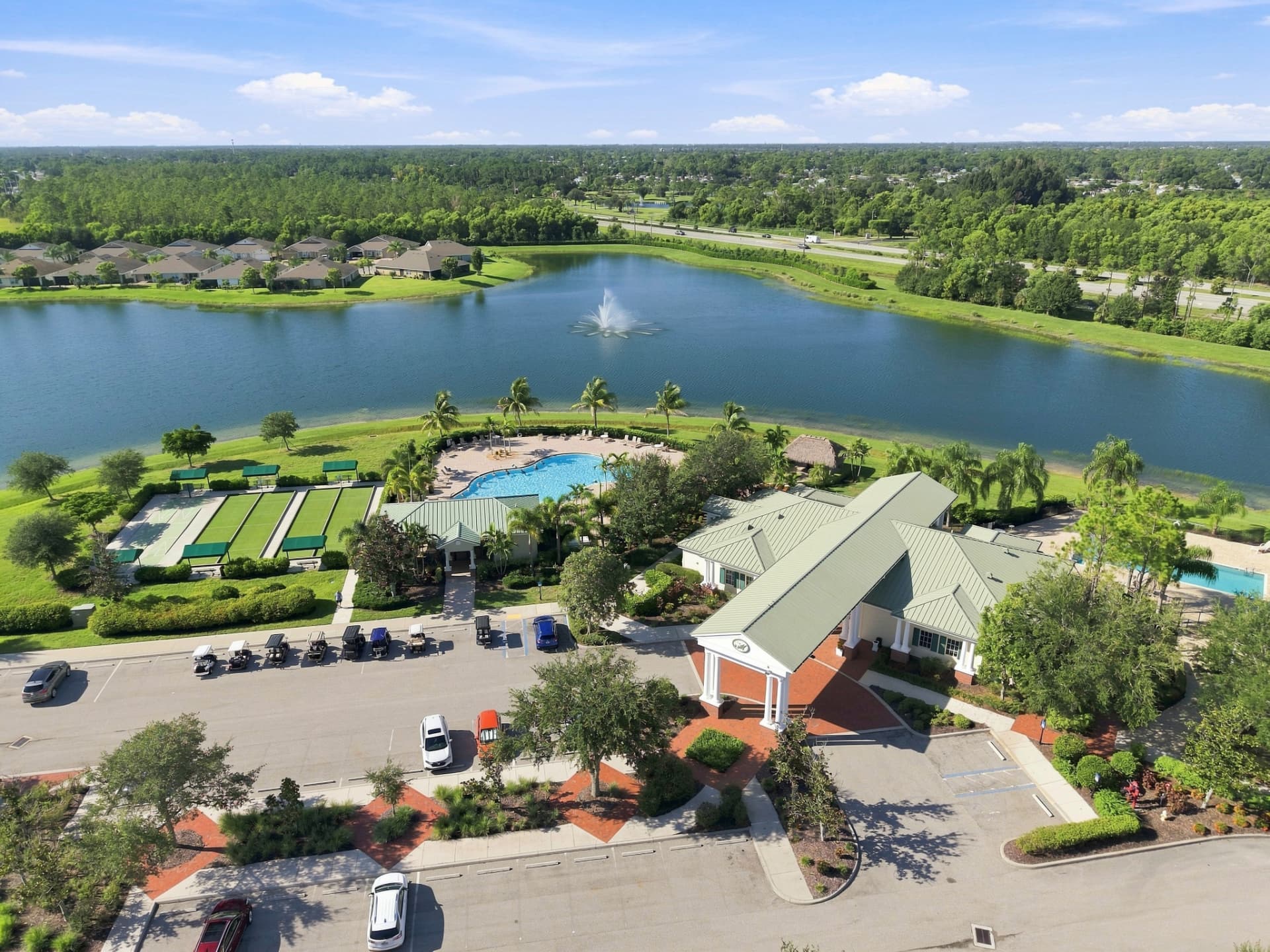 Drone photo of a community clubhouse with pool, lake and golf course in Southwest Florida