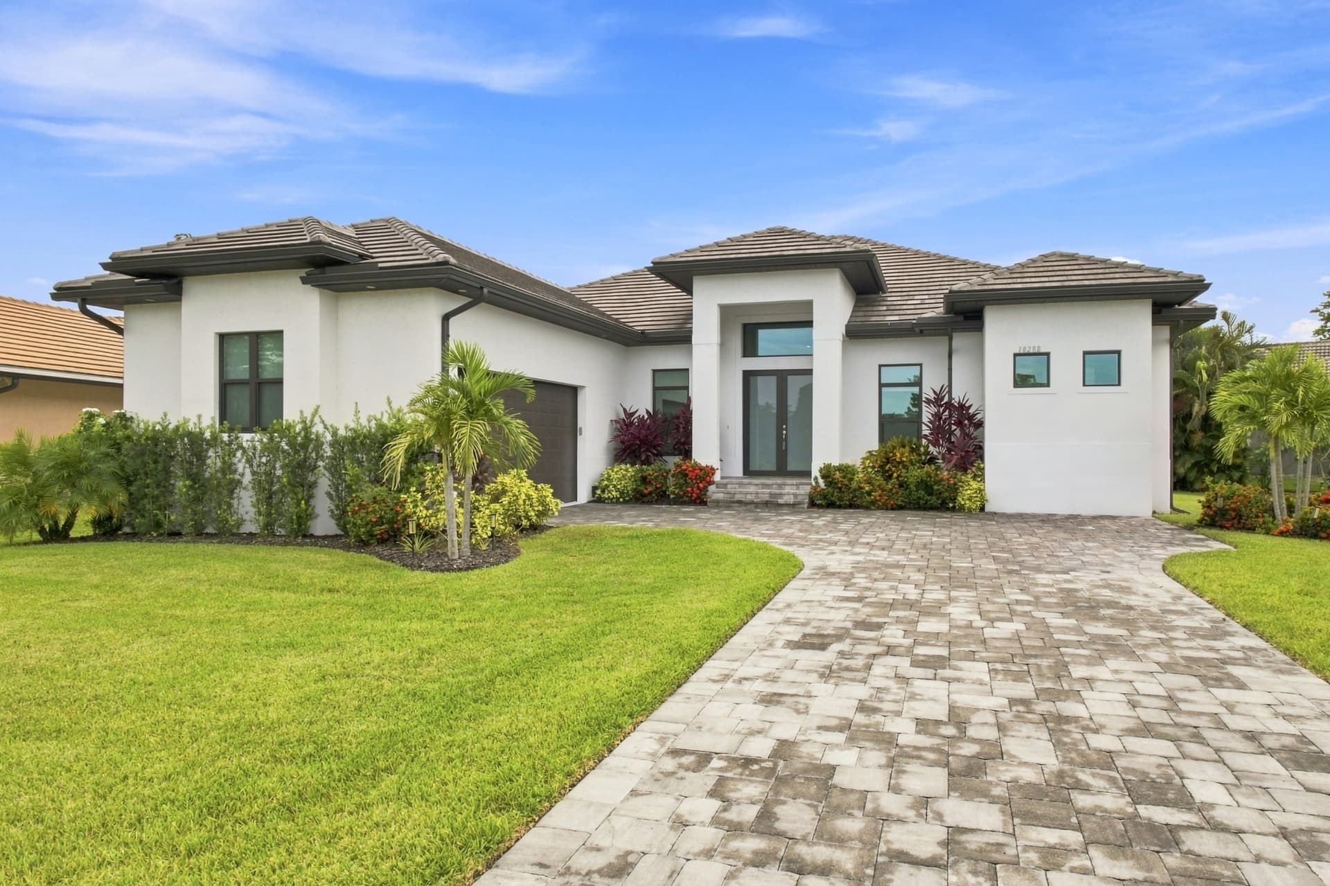 Front exterior of a Southwest Florida home with paver driveway and palm landscaping